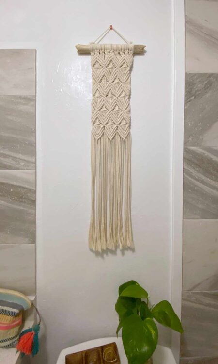 Macrame wall hanging on driftwood with vertical shape made with white cotton rope