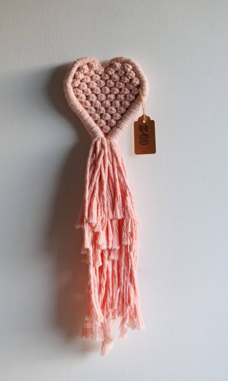 Pink macrame heart against white wall